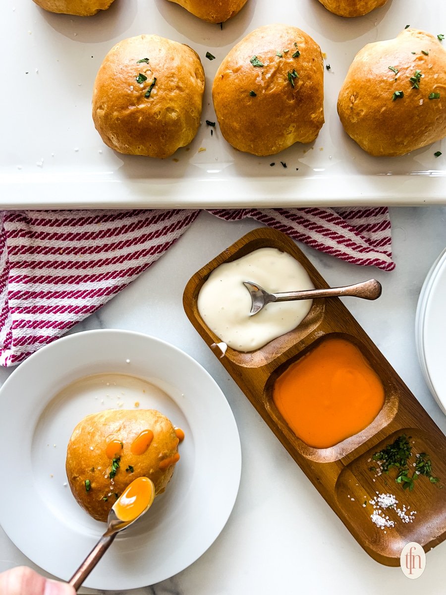 A plate and a platter of buffalo chicken dip bites and a platter of sauces.