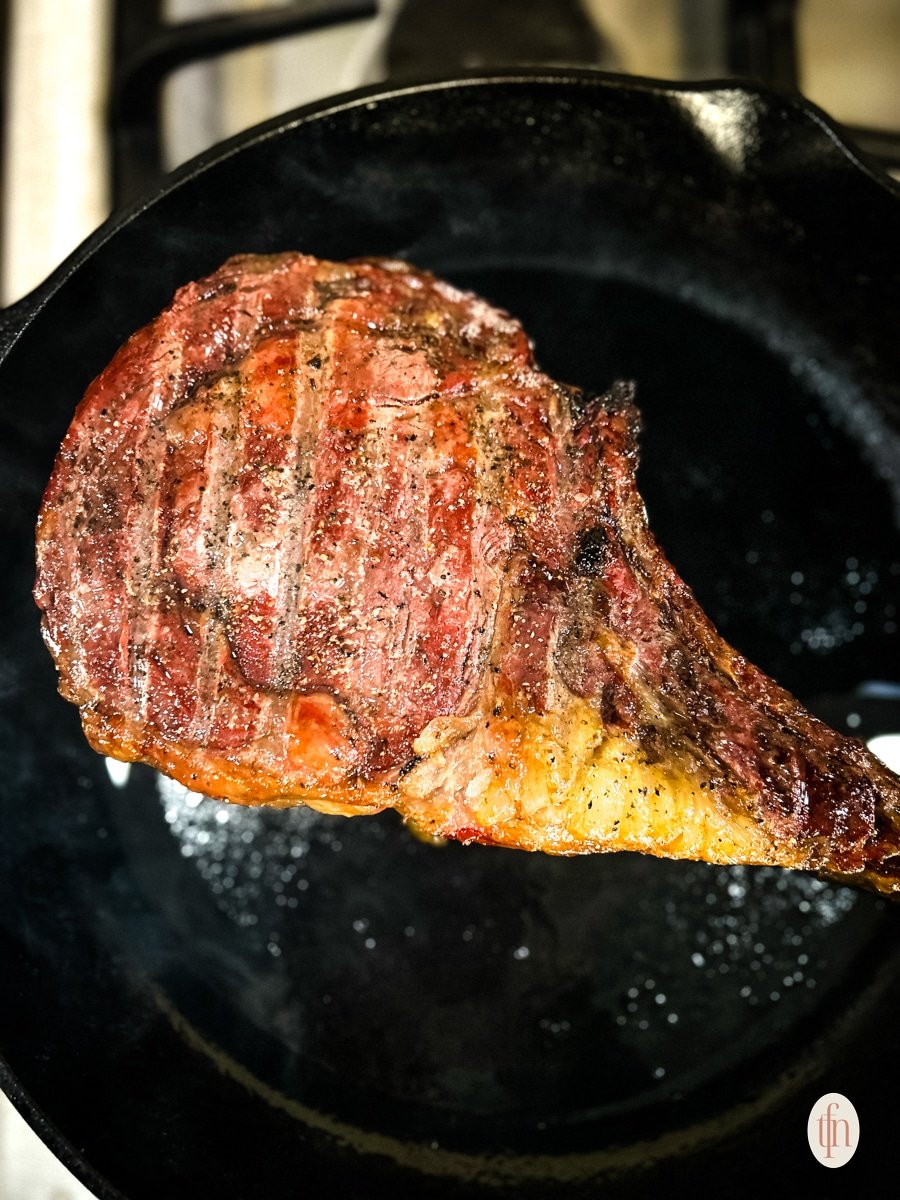 Cooked cowboy ribeye on a skillet