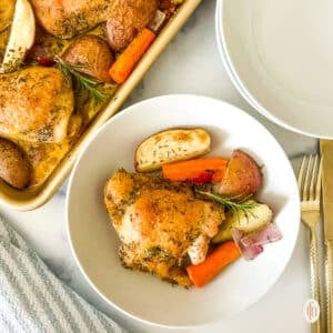Sheet pan chicken thighs plated with roasted vegetables and fresh herbs.