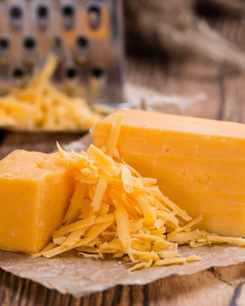 Shredded cheddar cheese in between two blocks of cheese.