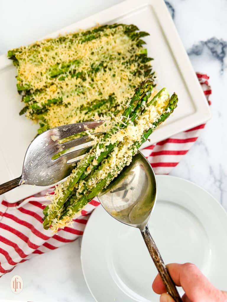 Getting a portion of asparagus casserole using spoon and fork.