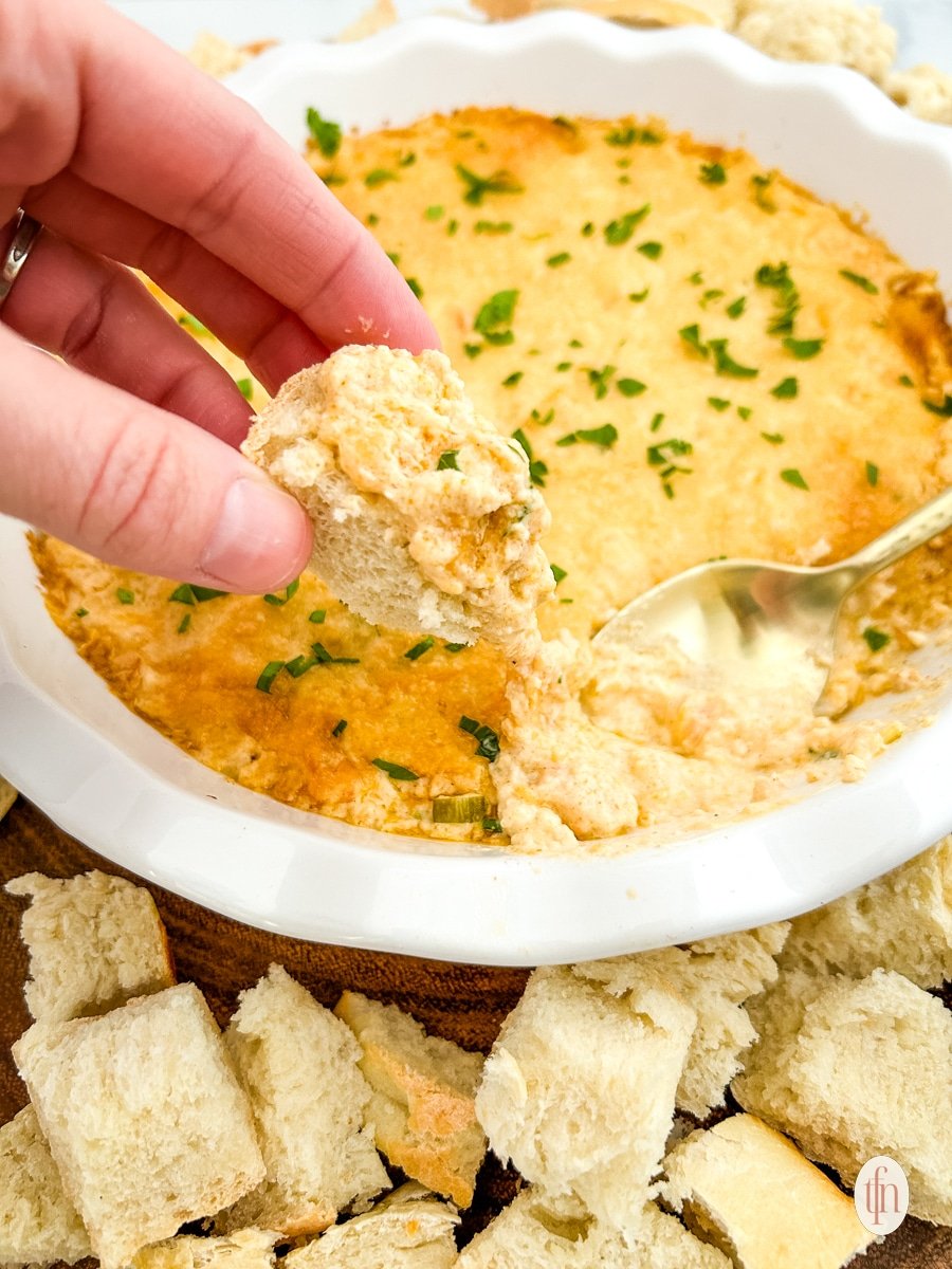 Croutons dipped in a bowl of cajun crab dip with shrimp.