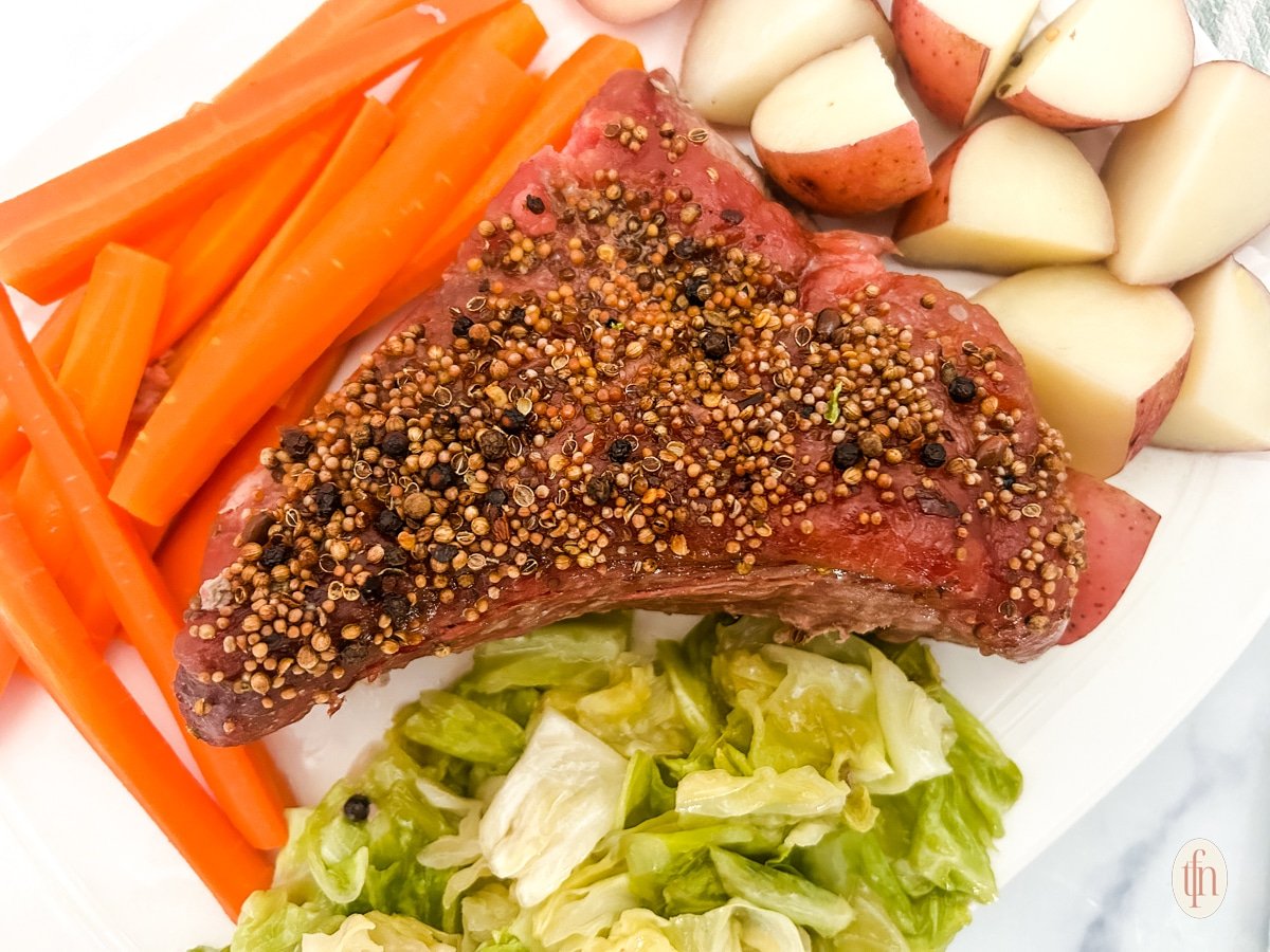 Dutch oven corned beef with seasoning on top and vegetables on the side.
