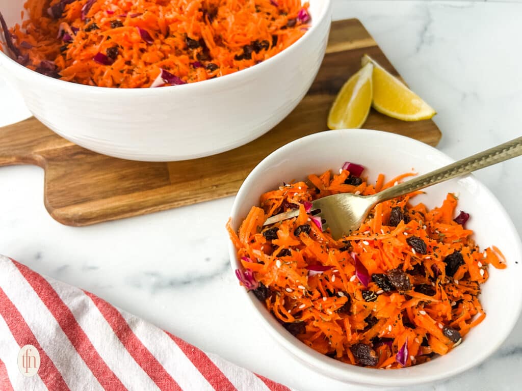 Shredded carrot in a white bowl with fork.