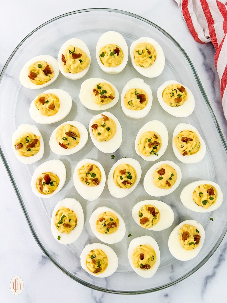 Spicy deviled eggs on a glass serving dish.