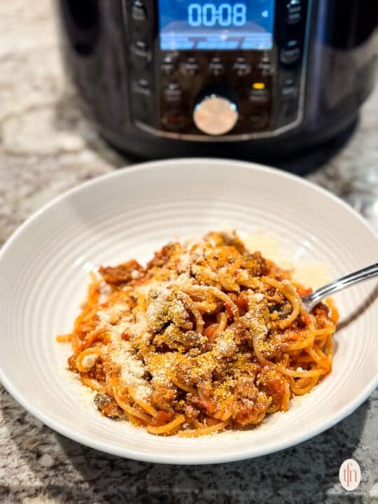 a bowl of spaghetti with an Instant Pot in the background.