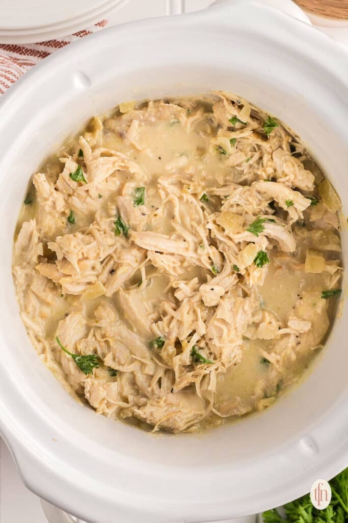 shredded chicken in the bowl of a slow cooker.