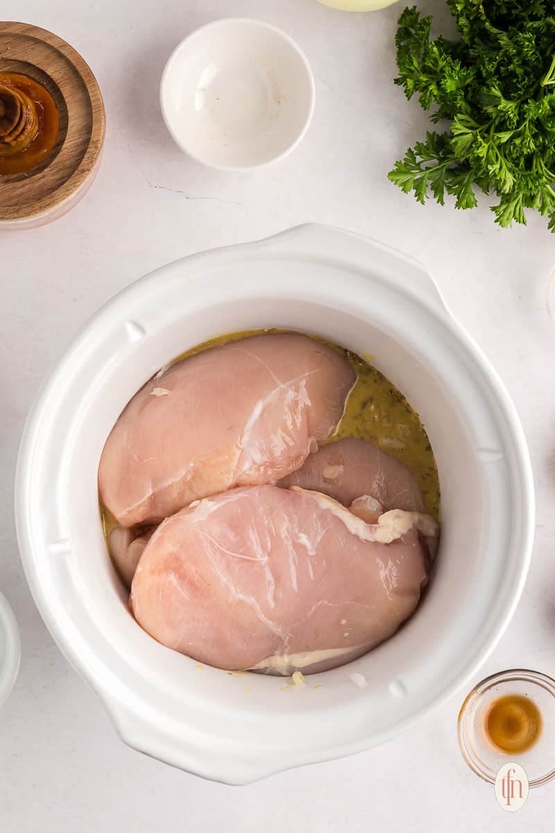 adding breasts to the honey garlic sauce in the crockpot.