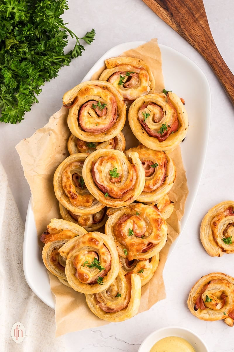 Ham and cheese pinwheels on a white serving platter.