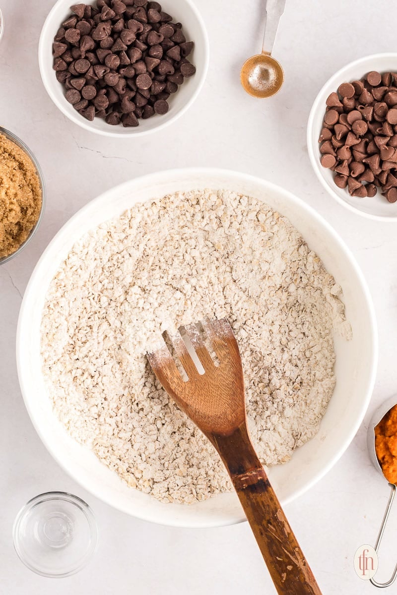 mixing dry ingredients: oats, flour, and spices in a mixing bowl.