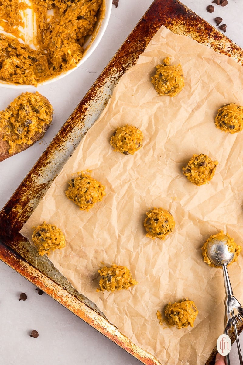 scooping cookie dough with a cookie scoop and placing on a baking sheet.