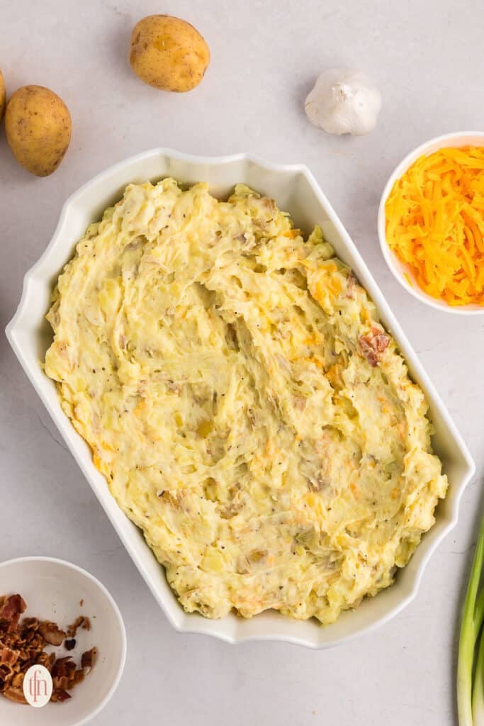 A mixture of mashed potatoes in a white casserole dish for twice baked mashed potatoes.