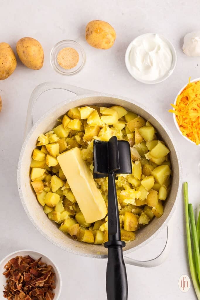 Potatoes and butter in a cooking pot with meat chopper.