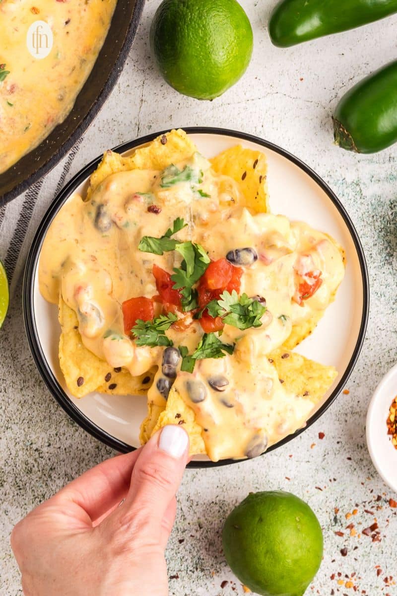 Nachos with cheese sauce, cilantro and tomato toppings.