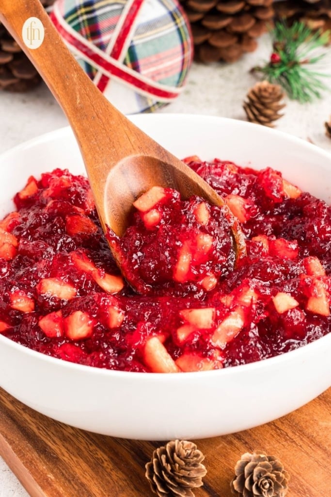 Jello mixture in a white bowl with wooden spoon.