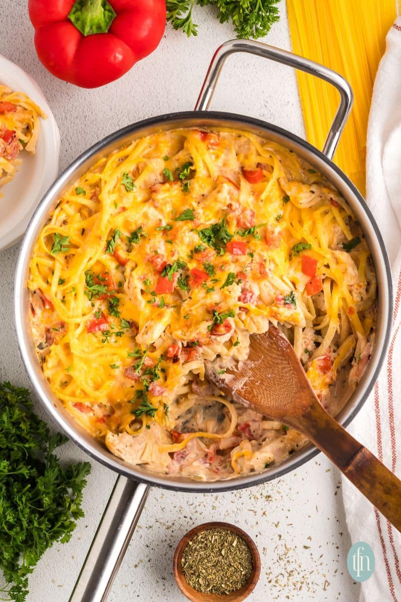 Cheese spaghetti in a pan with a wooden spoon.