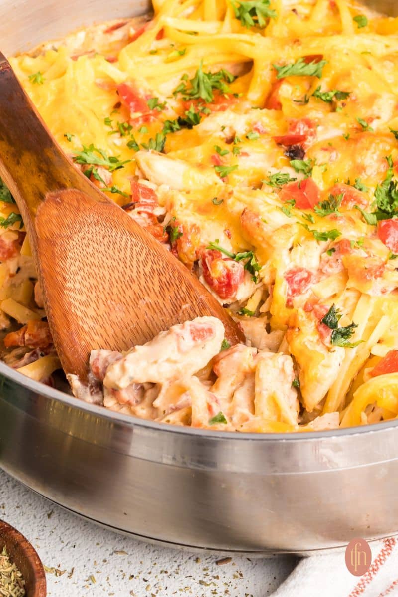 Cheese spaghetti in a pan with a wooden spoon.