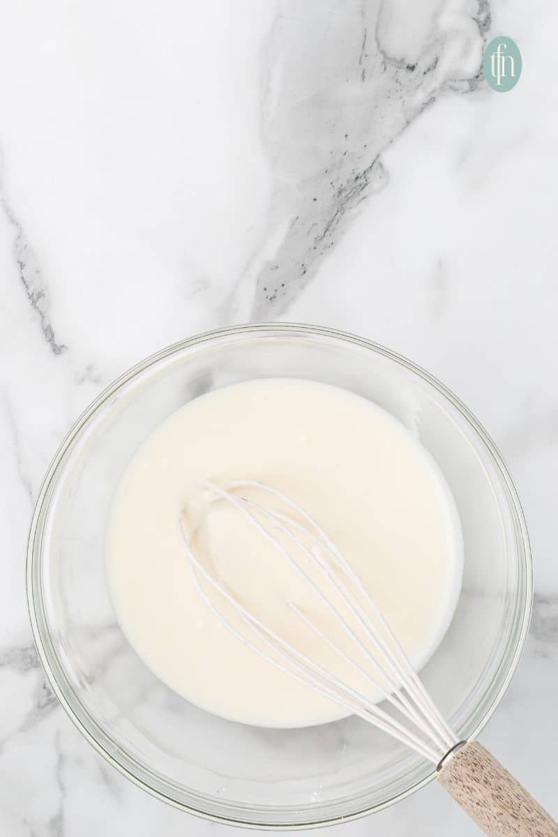 A bowl of glaze with whisk.