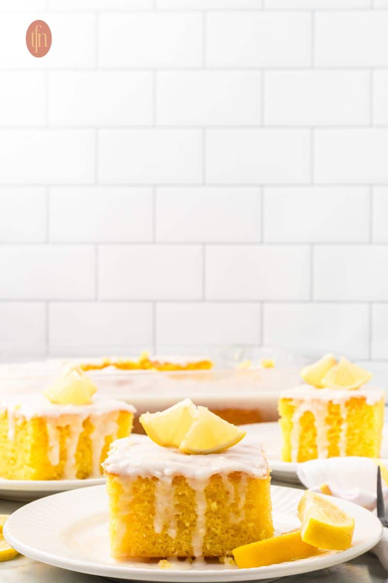 Three slices of cake with white glaze and slice of lemon on top.