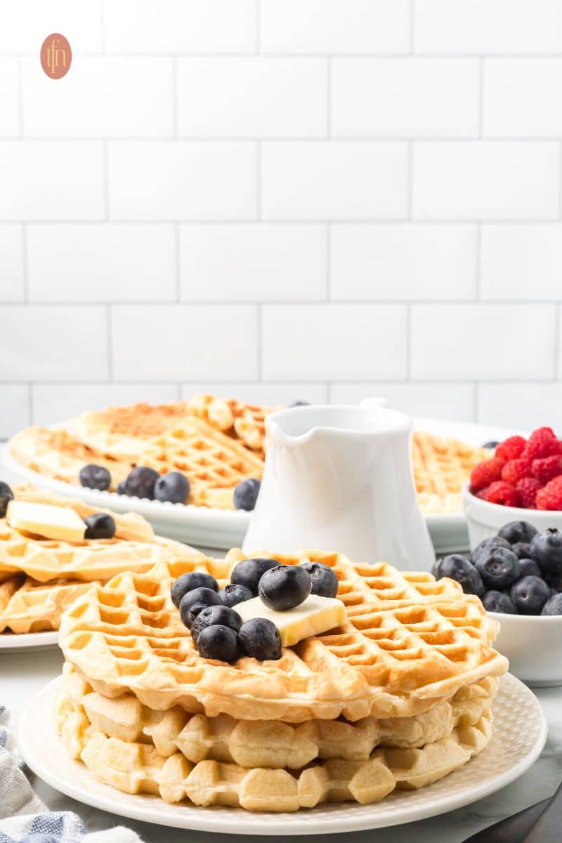 Stack of waffles with blueberries and butter.