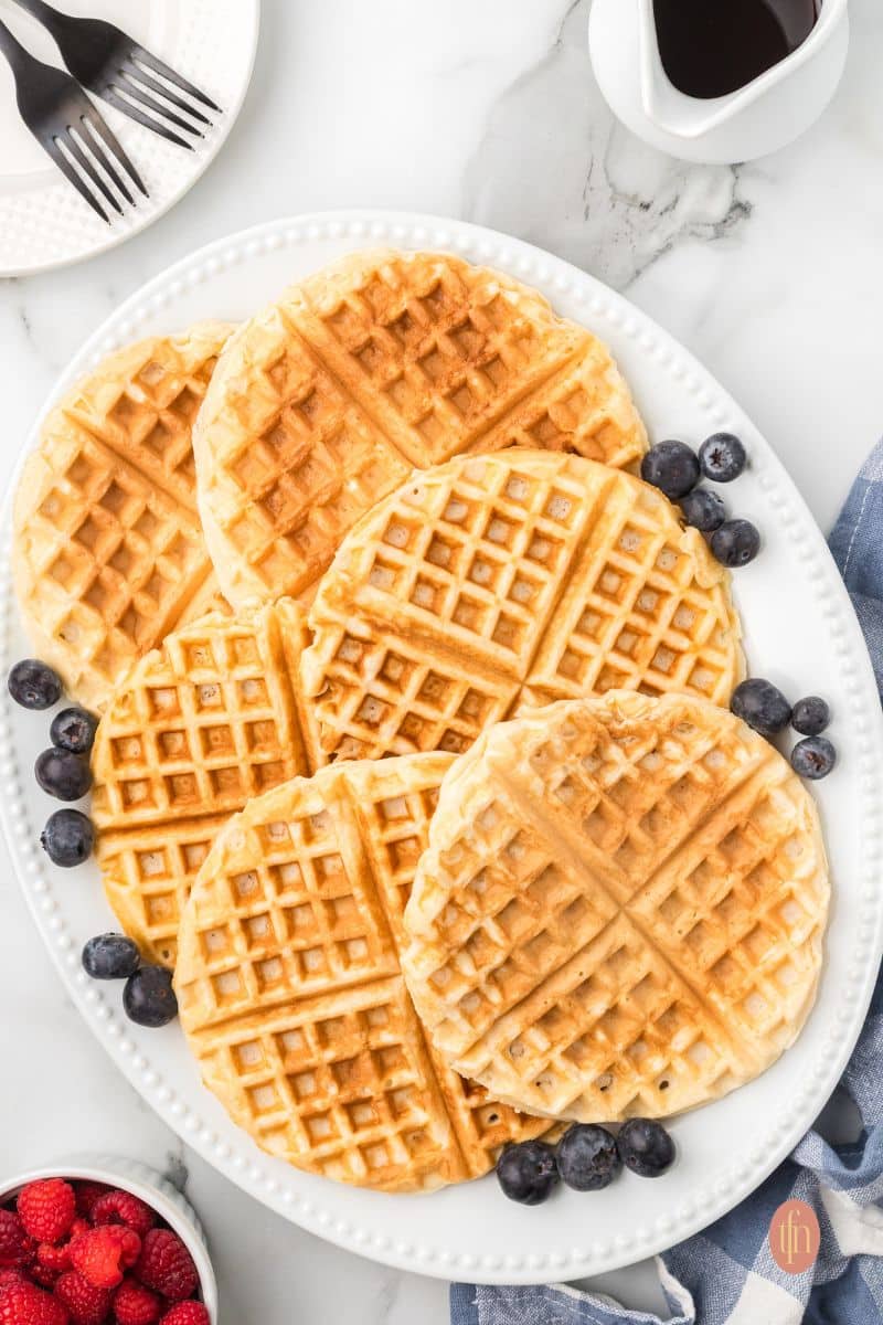 Waffles on a serving platter with blueberries.