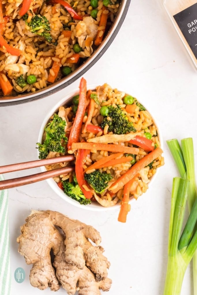 A bowl of fried rice with veggies and chicken.