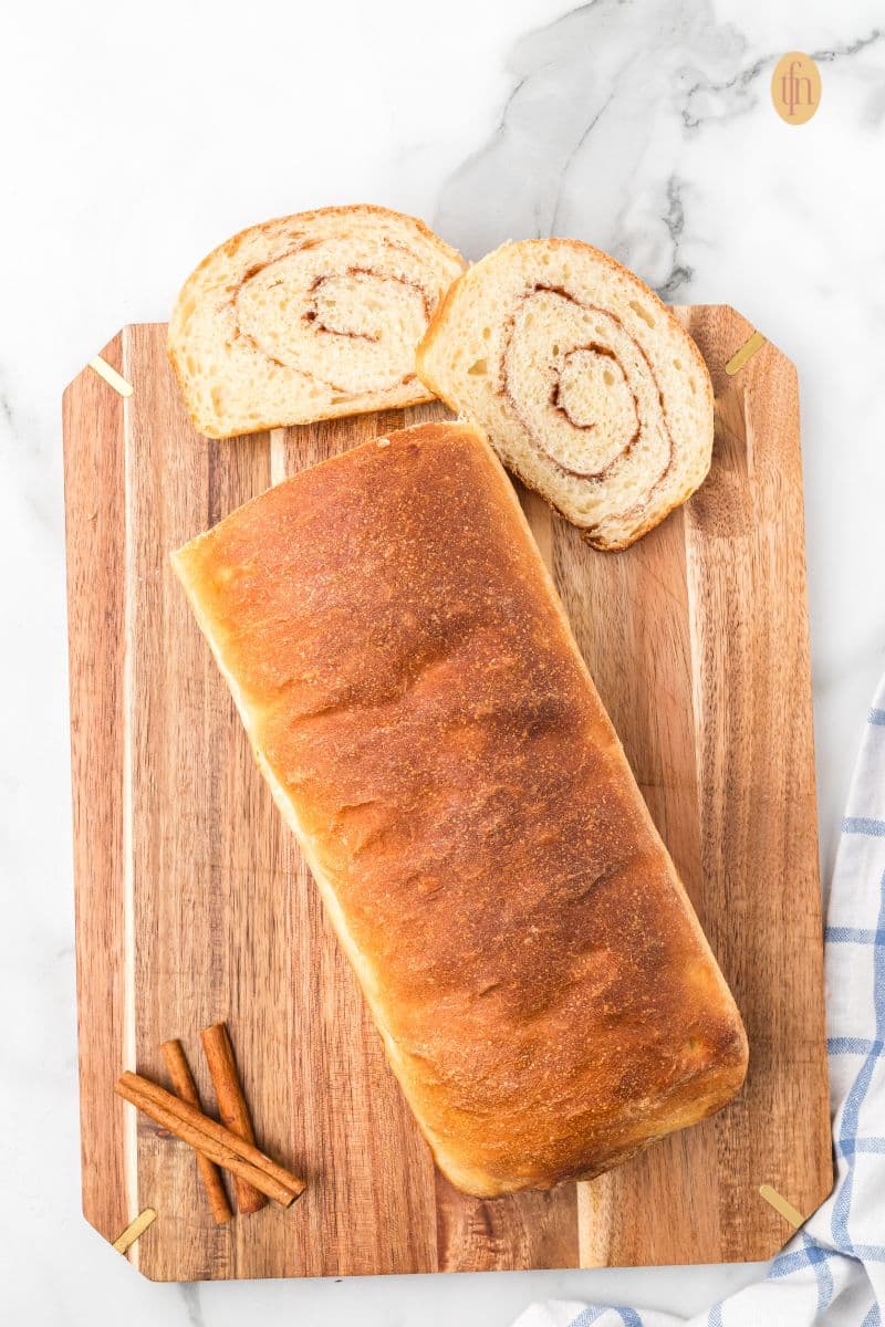 Baked loaf on a wooden board with cinnamon sticks.