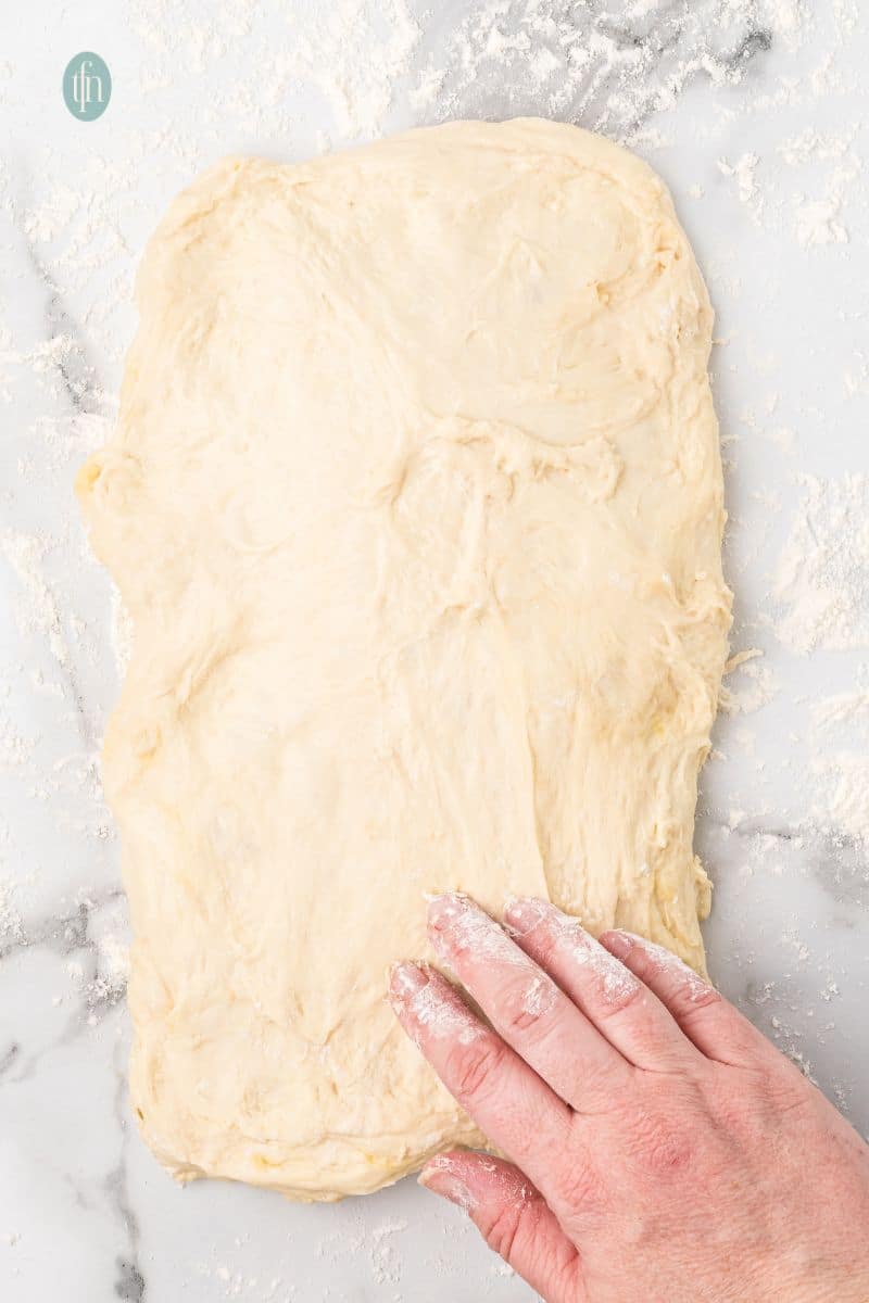 Flatten dough on a counter top.