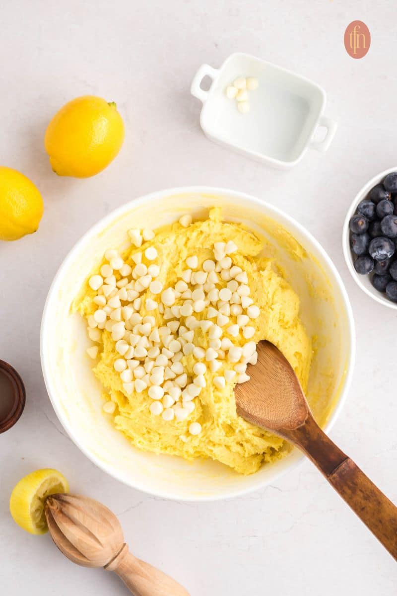 A creamed batter in a white bowl with white chocolate chips.