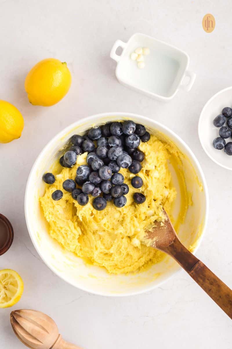 A creamed batter in a white bowl with blueberries.