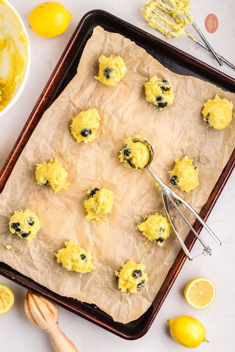 Cookie dough with a cookie scoop on a baking sheet.