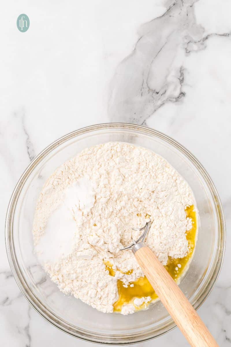 Raw ingredient on a bowl with dough whisk.