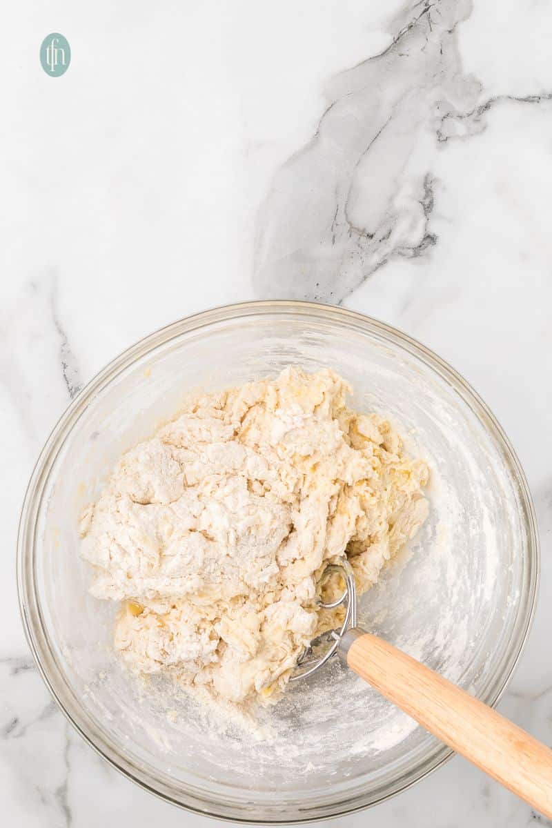 Shaggy dough on a bowl with dough whisk.