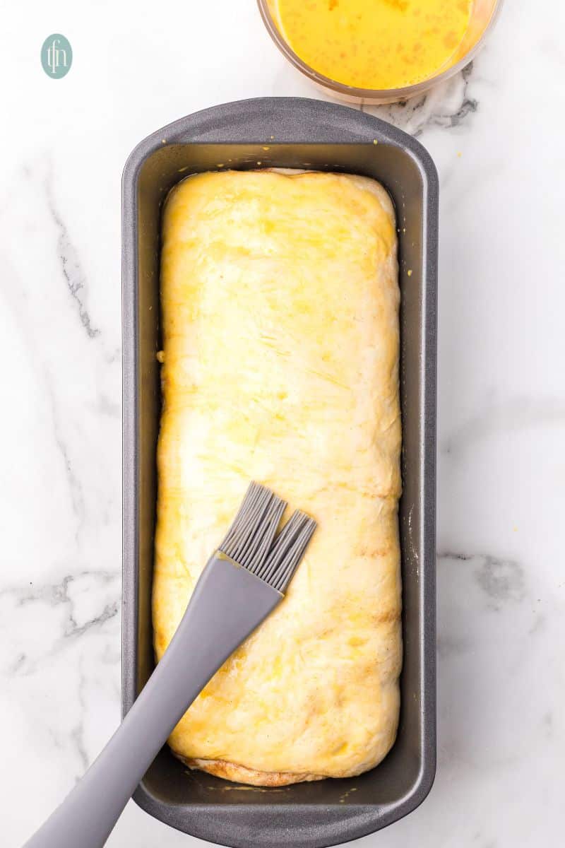 A pan of unbaked dough with pastry brush.