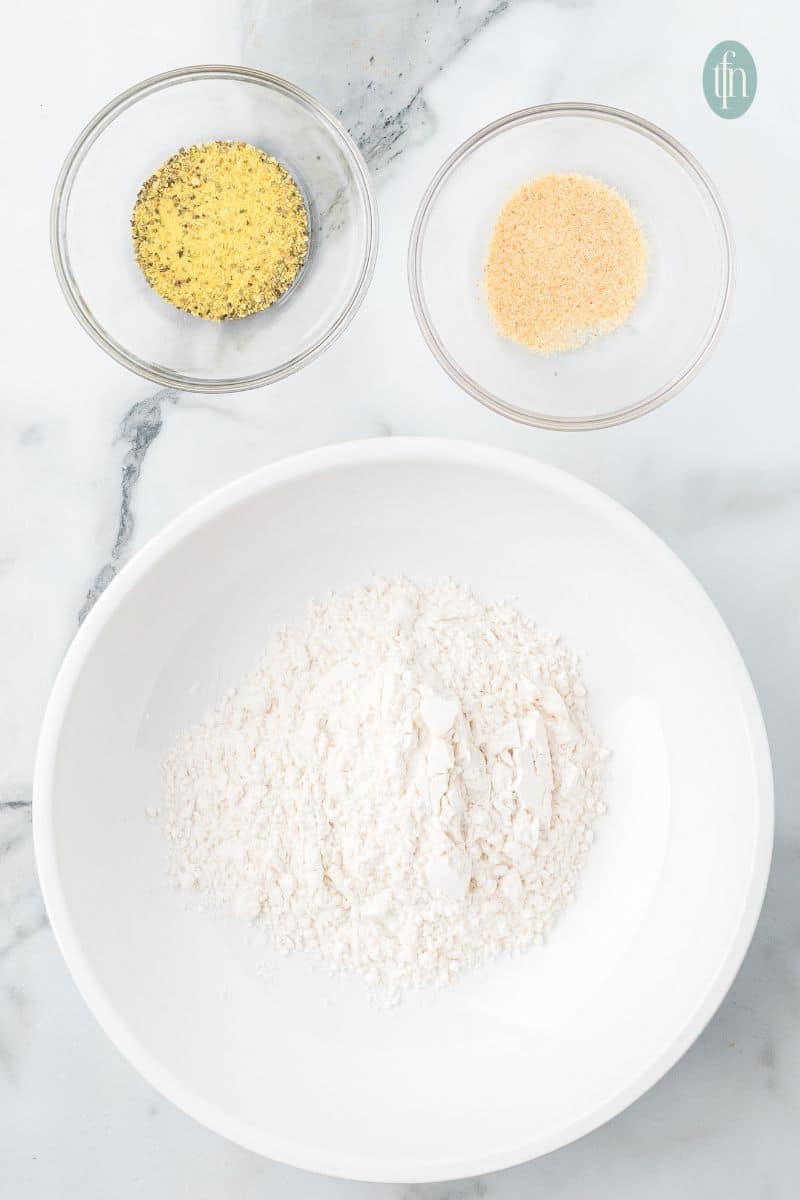 A bowl of flour, lemon pepper, and garlic powder.