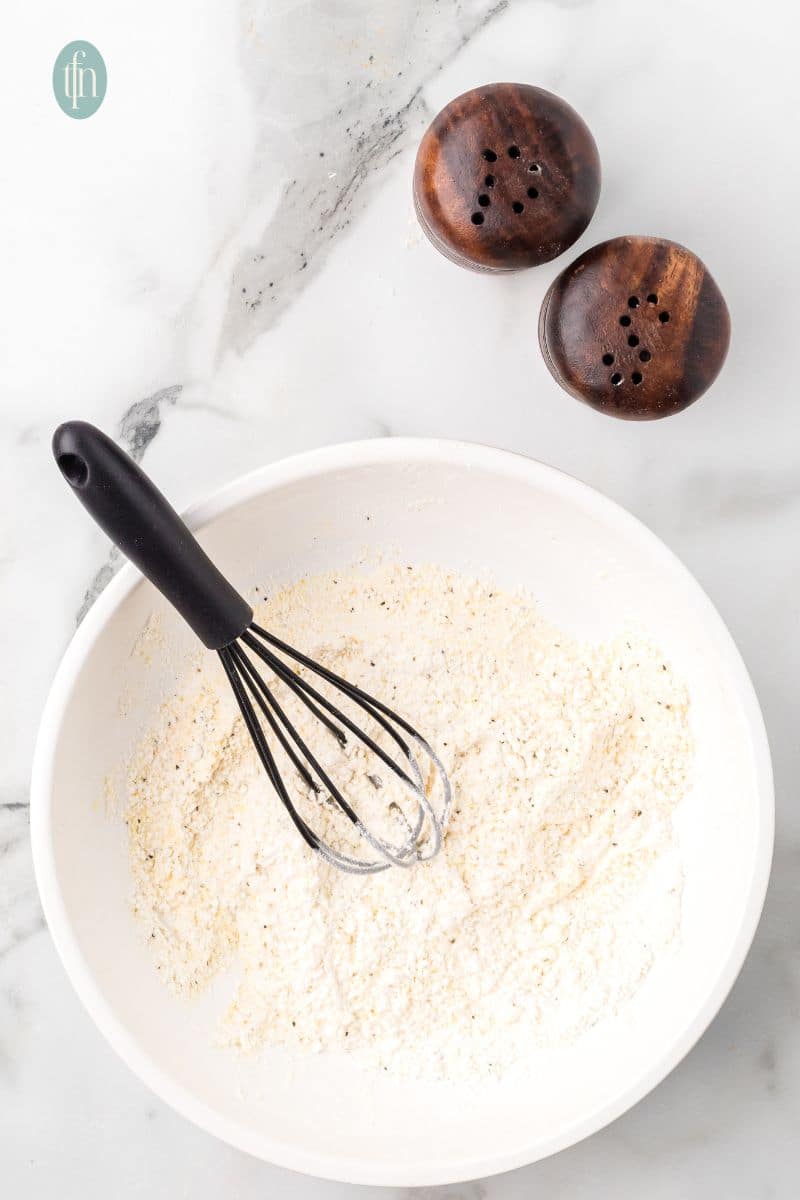 A bowl of dry ingredients with whisk.