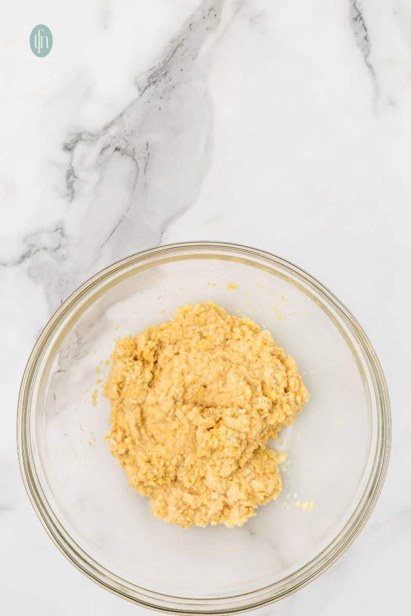 A large glass bowl holds the milk, egg, and breadcrumb mixture after being combined and allowed to soak.