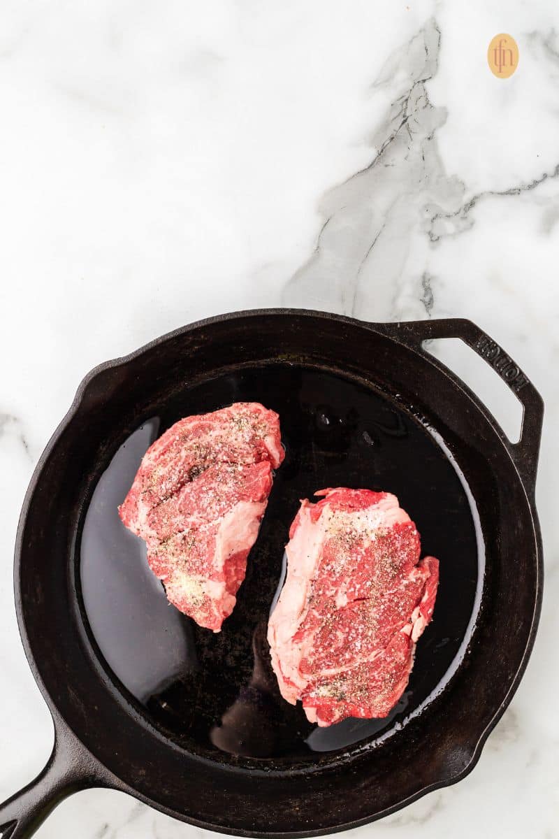 2 pieces of steak in a skillet pan.
