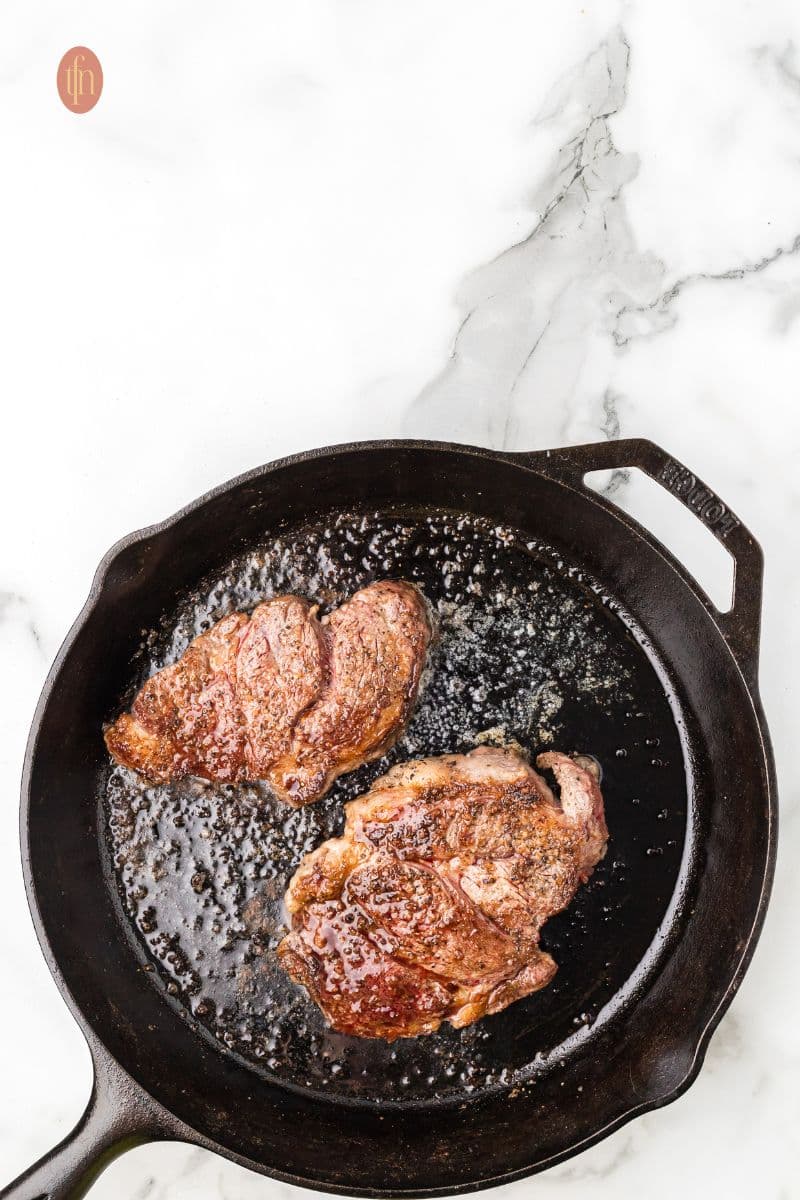 2 pieces of steak in a skillet pan.