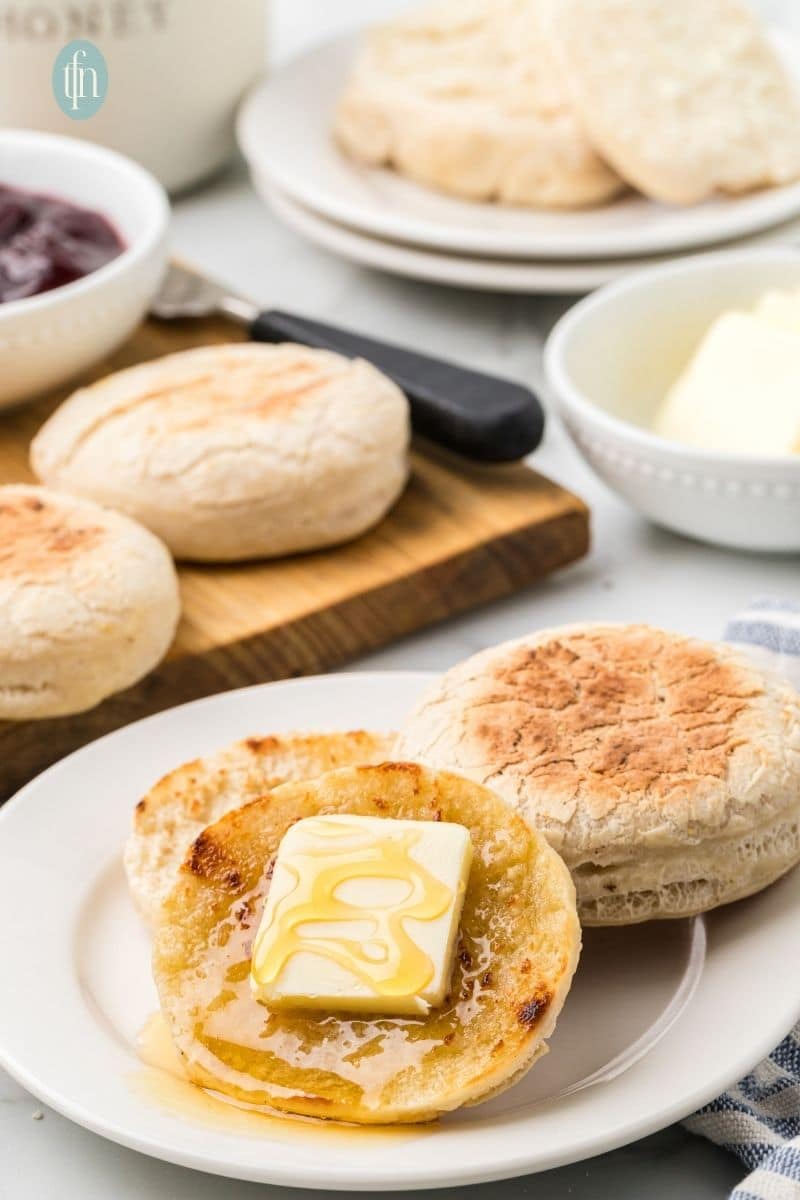A plate of english muffin with butter on top.