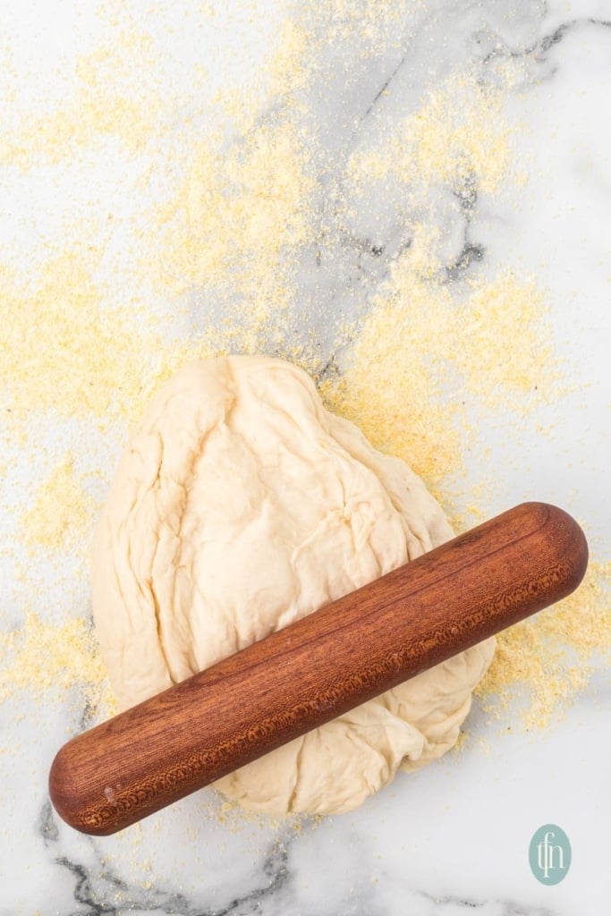 A flour-covered surface with a ball of dough and rolling pin on top.