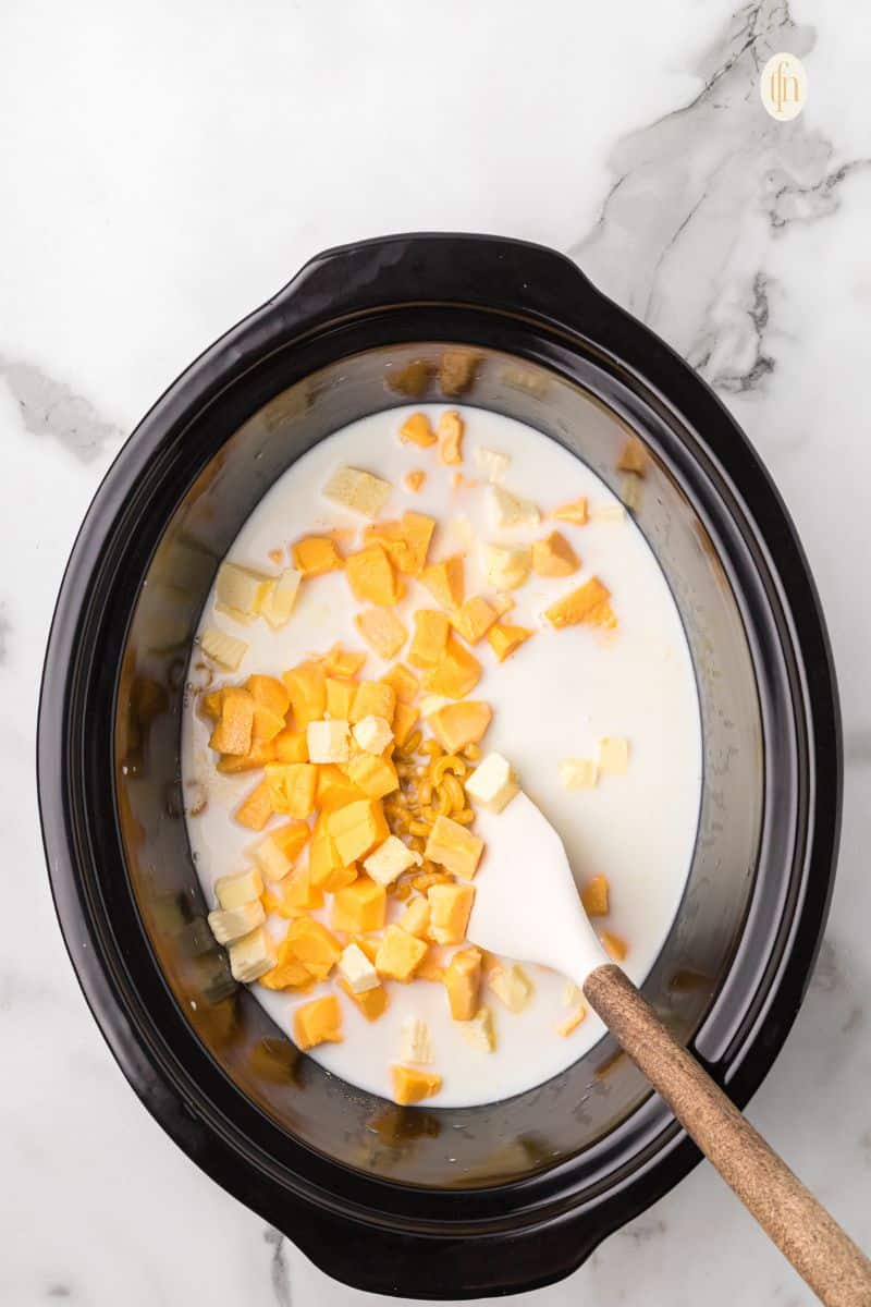 Crockpot with macaroni mixture and a ladle.