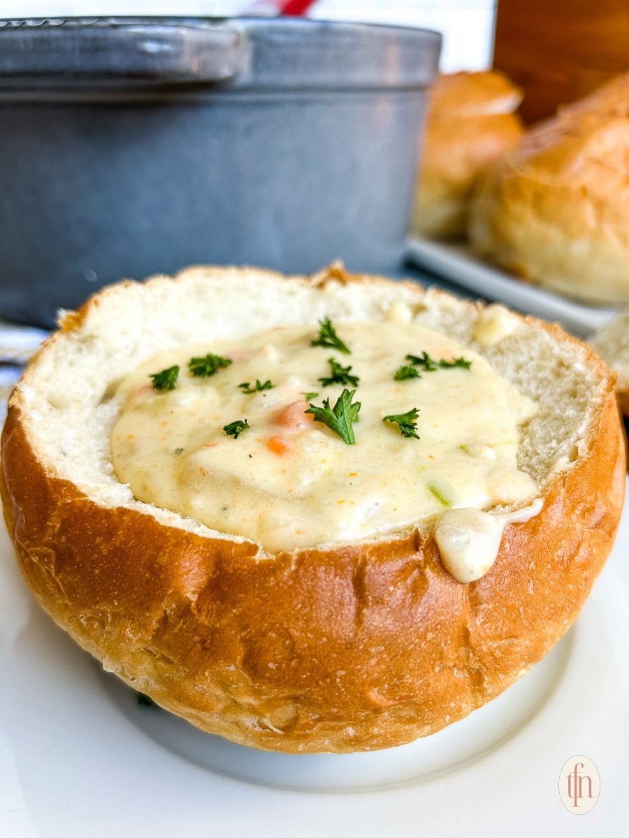 Close up of San Francisco Clam Chowder in a bread bowl on a white plate.