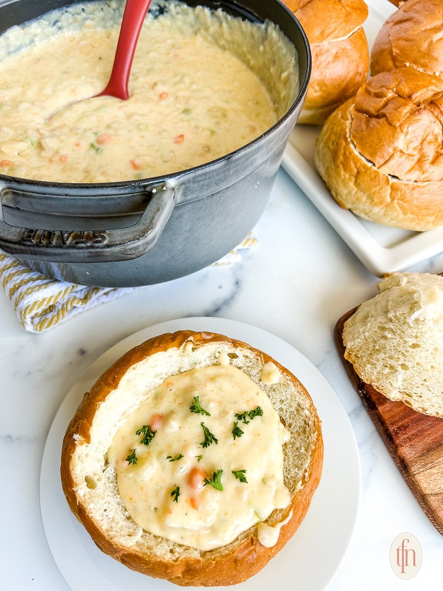 San Francisco Clam Chowder in a bread bowl on a white plate.