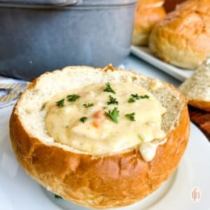 San Francisco Clam Chowder in a bread bowl on a white plate.