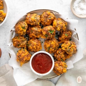 Bisquick sausage balls on a large white platter with a small jar of dipping sauce on the side.