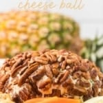Vertical image with text overlay that reads "PINEAPPLE cheese ball," featuring a close-up of the pecan-crusted cheese ball with a whole pineapple blurred in the background.