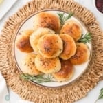 a plate of easy dinner rolls stacked with rosemary sprigs for garnish with a bowl of cranberries and butter for serving.