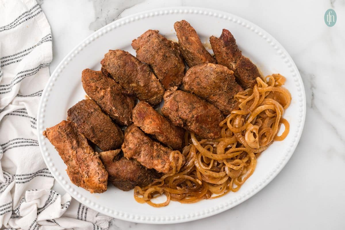 chunks of country style ribs on a platter served with onions cooked in the slow cooker