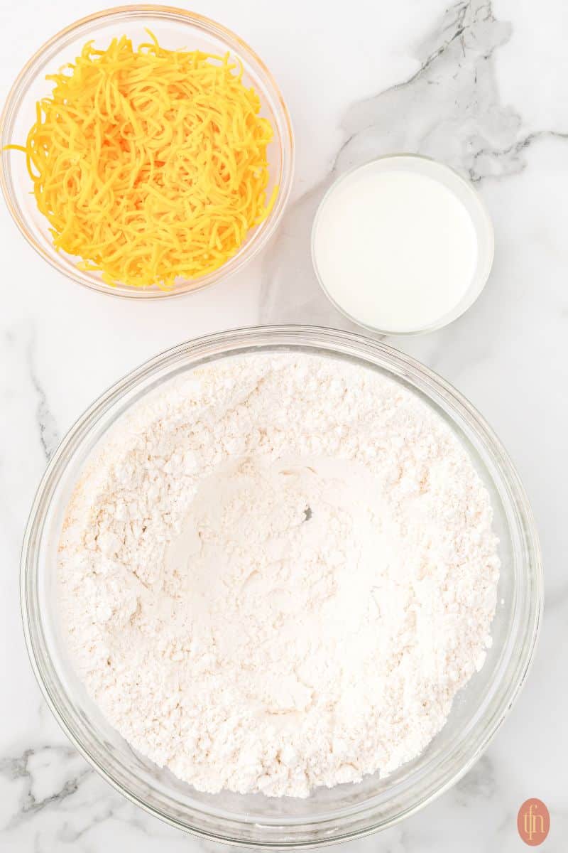 A bowl of flour, cheese, and milk.